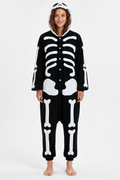 A woman modeling a black and white skeleton-themed hooded one-piece pajama or costume against a plain white studio background.
